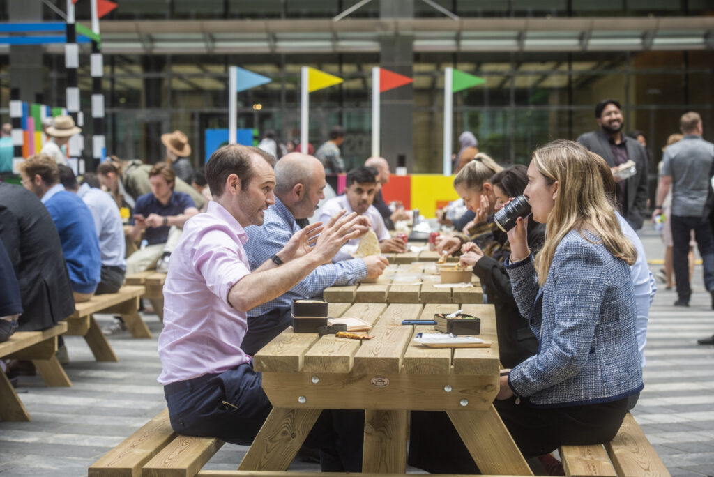Customers sat at a picnic table enjoying street food and drinks