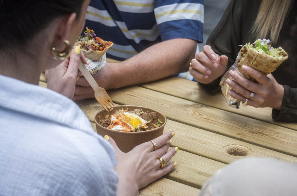 Salad bowls and wraps being eaten at a picnic table