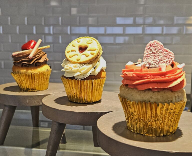 Three large cup cakes displayed on stalls